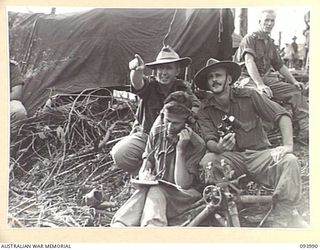 MOUNT SHIBURANGU, WEWAK, NEW GUINEA, 1945-07-12. MAJOR R.J. WISE, BATTERY COMMANDER, 2 BATTERY, 2/1 FIELD REGIMENT AND ARTILLERY ADVISER TO THE 2/8 INFANTRY BATTALION (1), WITH GUNNER G.R. ..