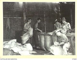 LAE-NADZAB, NEW GUINEA. 1944-07-25. PERSONNEL OF THE 8TH LINES OF COMMUNICATION SALVAGE DEPOT SORTING SCRAP CLOTHING AND CANVAS IN PREPARATION FOR SHIPMENT TO THE MAINLAND. IDENTIFIED PERSONNEL:- ..