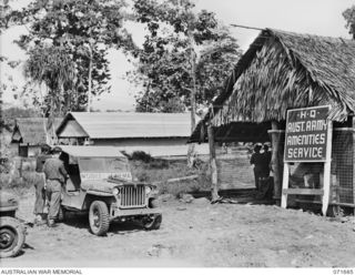 LAE, NEW GUINEA. 1944-03-25. A JEEP USED WITH MOBILE CINEMA EQUIPMENT, POSITIONED OUTSIDE THE MAIN BUILDING OF HEADQUARTERS ARMY AMENITIES SERVICE ATTACHED TO HEADQUARTERS LAE BASE SUB-AREA. GUINEA ..