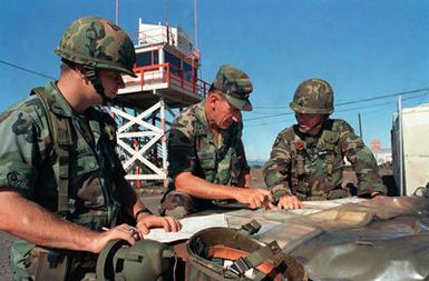 Brigade General John T. Quinn, center discusses battle plans for the 25th Infantry Division with 1ST Lieutenant Edward Neasson, his aide-de-camp, and LT. Colonel Richard J. Lane, right, executive officer of the 2nd Brigade, during training exercises at Bradshaw Army Air Field, Pohakuloa Training Area. The 25th Infantry Division is preparing for joint South Korean/US training exercise Team Spirit `84