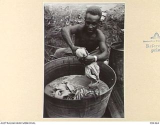 YAMIL 2, NEW GUINEA. 1945-07-20. MUNHOE, THE WASH-BOY FROM THE MAIN DRESSING STATION, 2/2 FIELD AMBULANCE, SCRUBBING AWAY IN A BIG TUB
