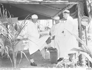 NAGADA, NEW GUINEA. 1944-08-02. THE SURGEON DISCUSSING CASE HISTORIES WITH HIS ASSISTANTS OUTSIDE THE OPERATING THEATRE OF THE 4TH FIELD AMBULANCE. IDENTIFIED PERSONNEL ARE:- WX3324 ..