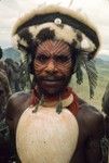 Man with elaborately painted face and wig with marsupial fur, wearing a specially fine baler shell for a ceremony