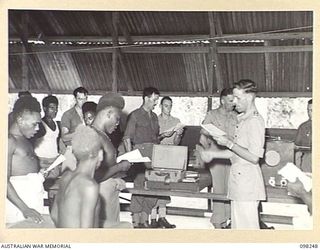 LAE, NEW GUINEA. 1945-10-10. CHAPLAIN K.M. PITHER CONDUCTING A SERVICE IN PIDGIN ENGLISH AT THE AUSTRALIAN NEW GUINEA ADMINISTRATIVE UNIT NATIVE HOSPITAL
