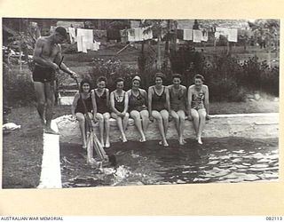 LAE, NEW GUINEA. 1944-10-31. CORPORAL E.L. BUCKMAN, 2/8 GENERAL HOSPITAL, INSTRUCTS PRIVATE V. DAVIDSON (2), AT THE AUSTRALIAN NEW GUINEA ADMINISTRATIVE UNIT SWIMMING POOL WITH THE ASSISTANCE OF A ..