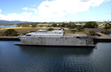 Aerial port side view of the US Navy (USN) experimental High Speed Vehicle 2 (HSV 2) Swift tied up pier side on the North side of Ford Island, Pearl Harbor, where it will participate in the Exercise RIM OF THE PACIFIC (RIMPAC) 2004. RIMPAC is the largest international maritime exercise in the waters around the Hawaiian Islands. This years exercise includes seven participating nations: Australia, Canada, Chile, Japan, South Korea, the United Kingdom and the United States. RIMPAC is intended to enhance the tactical proficiency of participating units in a wide array of combined operations at sea, while enhancing stability in the Pacific Rim region