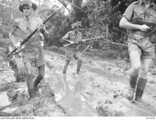 1942-10-01. NEW GUINEA. MILNE BAY. AUSTRALIAN TROOPS PLOUGH THROUGH THE MUD AT MILNE BAY SHORTLY AFTER THE UNSUCCESSFUL JAPANESE INVASION ATTEMPT