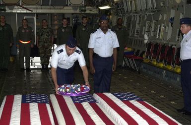 United States Air Force (USAF) Colonel (COL) Finnegan, Vice Commander (VC) of the 36th Wing, places a wreath on transfer case at a repatriation ceremony held at Andersen Air Force Base (AFB), Guam, while Lieutenant Colonel (LCOL) Reed (right) offers a prayer