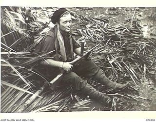 WEBER POINT, MALALAMAI,NEW GUINEA, 1944-02-09. PRIVATE W. HANNAFORD, "B" COMPANY, 30TH INFANTRY BATTALION, RESTING ON PALM FRONDS ON A SWAMPY TRACK ON THE WAY TO YAGOMAI TO LINK WITH AMERICAN ..