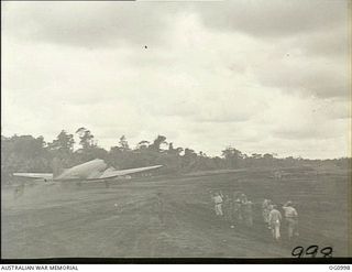 AITAPE, NORTH EAST NEW GUINEA. 1944-04-25. AMERICANS AND AUSTRALIANS STANDING ON THE SIDE OF THE RUNWAY WATCH THE ARRIVAL OF THE FIRST DOUGLAS TRANSPORT AIRCRAFT AS IT LANDS ON TADJI AIRSTRIP, MADE ..