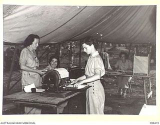 RABAUL, NEW BRITAIN. 1945-10-31. AUSTRALIAN ARMY MEDICAL WOMEN'S SERVICE PERSONNEL OF THE 118 GENERAL HOSPITAL, BUSY IN THEIR ORDERLY ROOM, IN TEMPORARILY ERECTED TENT ACCOMMODATION. IDENTIFIED ..