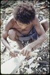 Canoe-building: man carves a nipawa (grasshopper) design on prow