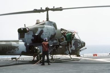 Maintenance crewmen aboard the amphibious assault ship USS SAIPAN (LHA-2) work on an AH-1J Sea Cobra helicopter attached to Marine Medium Helicopter Squadron 261 (HMM-261) during Operation Sharp Edge. Marines embarked aboard the SAIPAN have been sent to the U.S. Embassy in Monrovia, Liberia, to augment security and evacuate U.S. and foreign nationals from the fighting between government and rebel forces