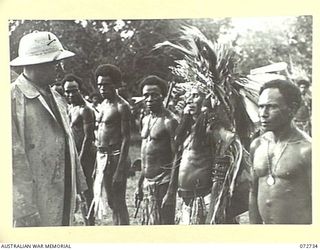 HIGITURA, NEW GUINEA. 1944-04-27. THE HONOURABLE E.J. WARD, MINISTER FOR EXTERNAL TERRITORIES IN THE AUSTRALIAN GOVERNMENT (1), SPEAKING WITH A HEADMAN WEARING CEREMONIAL DRESS DURING A PARADE HELD ..