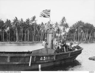 MILNE BAY, PAPUA. 1942-09. HOISTING THE UNION JACK ON A CAPTURED JAPANESE INVASION BARGE USED BY THEM IN THEIR ABORTIVE LANDING ATTEMPT AT MILNE BAY AND LATER SALVAGED AND PUT INTO USED BY ..