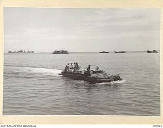 WEWAK BEACH, NEW GUINEA. 1945-10-18. AN AMPHIBIOUS DUKW OF 8 PORT OPERATING COMPANY NEARING THE BEACHHEAD LOADED WITH HIGH PRIORITY STORES FROM THE LIBERTY SHIP SAM FOYLE, SEEN IN BACKGROUND