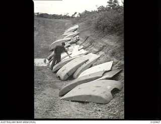 KIRIWINA, TROBRIAND ISLANDS, PAPUA. 1944-01-11. CORPORAL N. P. MEPHEW CHECKING OVER SOME BELLY TANKS WHICH ENABLE TROPICAL SPITFIRE AIRCRAFT OF NO. 79 (SPITFIRE) SQUADRON RAAF TO RANGE OVER NEW ..