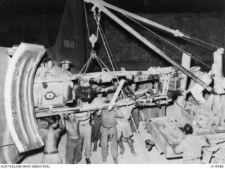 1943-04-01. NEW GUINEA. THREE TON AMERICAN TRUCKS DISMANTLED AND LOADED INTO TRANSPORT 'PLANES BY AMERICANS AND AUSTRALIANS FOR SHIPMENT TO WAU. (NEGATIVE BY N. BROWN)