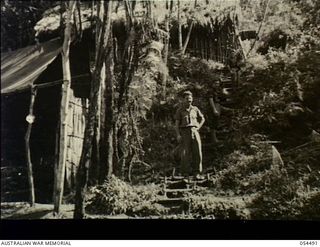 Guadagasal, New Guinea. 1943-07-21. The Sergeants' Mess and mens' sleeping quarters at the 17th Australian Infantry Brigade Headquarters, AIF. On the track up to the sleeping quarters are NX5161 ..