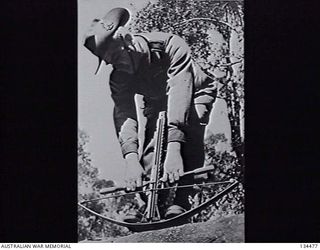 NEW GUINEA. 1943-02. SERGEANT J. W. WRIGHT, ONE OF ITS TWO DESIGNERS, DEMONSTRATING THE ARROWSPEED CROSS BOW GUN DESIGNED TO FIRE INCENDIARY, HIGH EXPLOSIVE AND OTHER TYPES OF ARROWS. (DONOR: L. J. ..