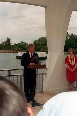 President William Jefferson Clinton speaks during a ceremony aboard the ARIZONA (BB-39) Memorial as Hillary Rodham Clinton stands by. The Clintons are in Hawaii to tour area military installations