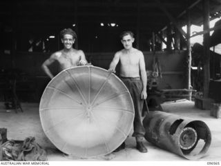 TOKO AREA, SOUTH BOUGAINVILLE. 1945-08-27. CORPORAL H.L. BOYD (1) AND STAFF SERGEANT BEAGLEY (2) MEMBERS OF 126 BRIGADE WORKSHOP, WITH A LIGHT REFLECTOR THEY MADE FOR THE OPERATING THEATRE, 106 ..