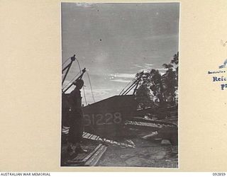 NANTAMBU, NEW BRITAIN. 1945-06. A MEMBER OF THE MILITARY HISTORY FIELD TEAM LOOKING AT AUSTRALIAN BARGES LINED UP ON THE BEACH