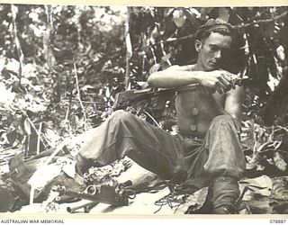BOUGAINVILLE ISLAND. 1945-02-03. WX26691 PRIVATE J SAMPSON "A" COMPANY, 9TH INFANTRY BATTALION, TAKING ADVANTAGE OF HIS REST PERIOD IN A COMPANY FORWARD POSITION TO CLEAN HIS BREN GUN