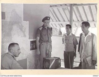 NAMANULA, NEW BRITAIN. 1945-11-21. MAJOR-GENERAL K.W. EATHER, GENERAL OFFICER COMMANDING 11 DIVISION, CONFERRING WITH SENIOR FORMOSAN AND KOREAN OFFICERS IN AN OFFICE AT HQ 11 DIVISION
