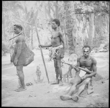 Seated man with a lime gourd and two other men, New Guinea, ca. 1936 / Sarah Chinnery