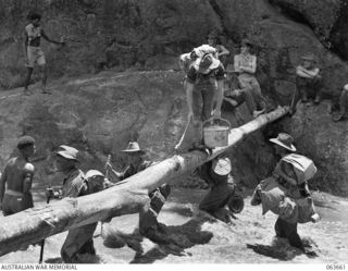 FARIA RIVER, NEW GUINEA. 1944-01-20. MEMBERS OF THE 2/5TH FIELD AMBULANCE AND ARTILLERY UNITS CROSSING THE FARIA RIVER ON THEIR WAY TO THE FRONT LINE