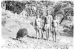 Group standing beside pig