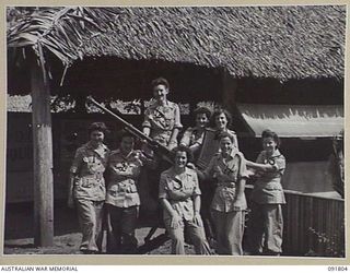 LAE, NEW GUINEA. 1945-05-15. CLERKS AND TYPISTS FROM THE OFFICE OF THE DEPUTY DIRECTOR OF ORDNANCE SERVICE, HEADQUARTERS FIRST ARMY, STAND AROUND A CAPTURED JAPANESE ANTI-AIRCRAFT GUN OUTSIDE THEIR ..