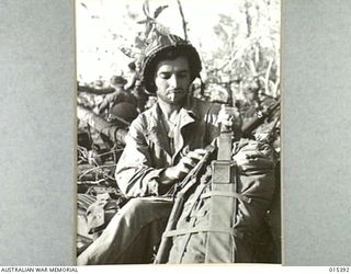 1943-08-03. ALLIED CAPTURE OF MUBO. SGT. TONI PORTER, OF SANTA CLARE, CALIFORNIA, RESTING WHILE ON HIS WAY TO THE FRONT LINE BETWEEN NASSAU BAY AND MUBO. AMERICAN AND AUSTRALIAN TROOPS DROVE THE ..