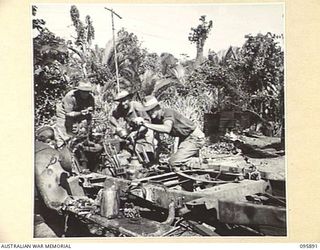 WIRUI BEACH, WEWAK, NEW GUINEA. 1945-09-04. A JAPANESE TRUCK BEING REFITTED BY MEMBERS OF 2/11 INFANTRY BATTALION. PRIVATE A.J. CLARK (1), IS WORKING ON THE RADIATOR WHILE PRIVATE L. ROWLES (2), ..