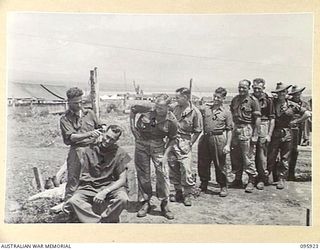 WEWAK POINT, NEW GUINEA. 1945-08-29. PRIVATE J.M. CARTER (1), CUTTING THE HAIR OF PRIVATE DOHERTY (2), WHILE OTHER MEMBERS OF 2/8 INFANTRY BATTALION WAIT THEIR TURN