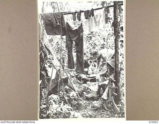 1943-08-10. NEW GUINEA. MOUNT TAMBU FIGHTING. SGT. ERNIE SPENCER, OF BRUNSWICK, VIC., STAFF SERGEANT IVAN SMITH, OF HAMILTON, VIC., AND CPL. LAURIE BARKER, OF MANLY, N.S.W., COOKING A MEAL AT THE ..