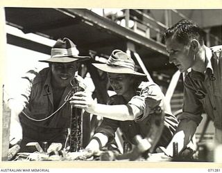 PORT MORESBY, PAPUA, 1944-03-21. NX145540 CORPORAL W. HOWARD (1) WITH TX6217 LIEUTENANT T.L. MOLLOY (2), MEMBERS OF THE 1ST BULK PETROLEUM STORAGE COMPANY, (NEW GUINEA FORCE), PICTURED WITH MR. R. ..