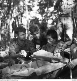 PAPUA, NEW GUINEA. 1942-10. JAPANESE PRISONER CAPTURED NEAR NAURO. HE HAD BEEN OVERWORKED AND WAS NEARLY STARVING WHEN TAKEN PRISONER. HE IS SEEN BEING CARED FOR BY AUSTRALIAN STRETCHER BEARERS