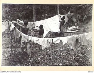 YAMIL 2, NEW GUINEA. 1945-07-20. PRIVATE D.R. HARTMANN-HUDSON, IN CHARGE OF LAUNDRY AT THE MAIN DRESSING STATION, 2/2 FIELD AMBULANCE (1) DIRECTING HIS TWO WASH BOYS AT THEIR JUNGLE LAUNDRY. THE ..