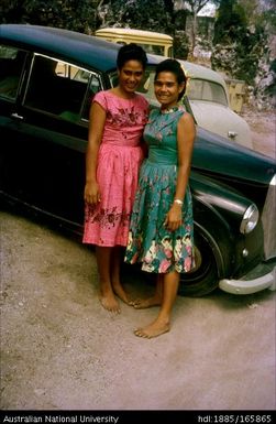 Two women in front of cars