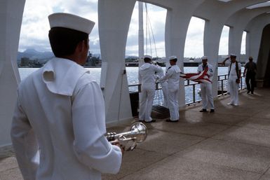 A bugler stands by as the American flag is folded during a memorial service for a crew member of the battleship USS ARIZONA (BB 39). During the service, a canister containing the crew member's remains is being dropped into an opening in the ARIZONA'S sunken hull, thus committing them to the submerged vessel