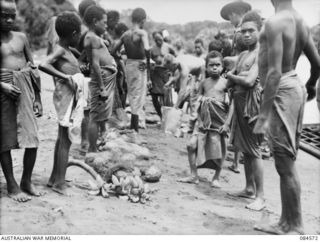 LABU, NEW GUINEA. 1944-12-17. 43 LANDING CRAFT COMPANY PERSONNEL AMONG NATIVES TRADING THEIR BISCUITS AND TINNED MEAT FOR FRUIT