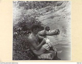 BRANDI, NEW GUINEA, 1945-09-07. PRIVATE G.S. BOWRING, 35 INFANTRY BATTALION, WASHING HIS TOWEL THE EASY WAY