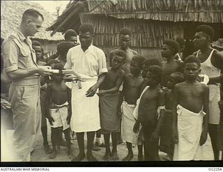 TOROKINA, BOUGAINVILLE ISLAND, SOLOMON ISLANDS. C. 1945-02. RAAF PADRE FLIGHT LIEUTENANT J. HENDERSON, NYNGAN, NSW, CHATS WITH SOME OF THE NATIVE CHILDREN AFTER CONDUCTING A CHURCH SERVICE AT A ..