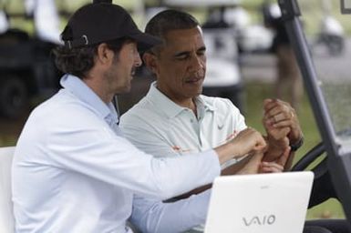 Barack Obama confers with Robert Baker after he plays golf in Kaneohe Bay, Hawaii, December 24, 2014