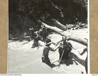 FARIA RIVER, RAMU VALLEY, NEW GUINEA. 1944-01-18. MEMBERS OF NO. 7 BATTERY, 2/4TH FIELD REGIMENT, WADING THROUGH THE FAST FLOWING FARIA RIVER ON THEIR WAY TO FORWARD POSITIONS