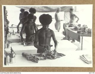 17 MILE, PORT MORESBY AREA, NEW GUINEA. 1943-12-04. NATIVE BOYS IRONING CLOTHES AT THE 9TH AUSTRALIAN DIVISION MOBILE LAUNDRY