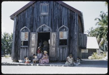 Exterior view of the Church of Zion, Palmerston Island, with unidentified women and children sitting outside