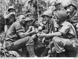 1943-10-01. NEW GUINEA. NADZAB AREA. AUSTRALIAN TROOPS CHAT TO AMERICAN PARATROOPS WHO LANDED AT NADZAB. LEFT TO RIGHT - SAPPER C. MACKENZIE OF WILLOUGHBY, N.S.W.; SAPPER RON BROWN OF BULLI, N.S.W. ..